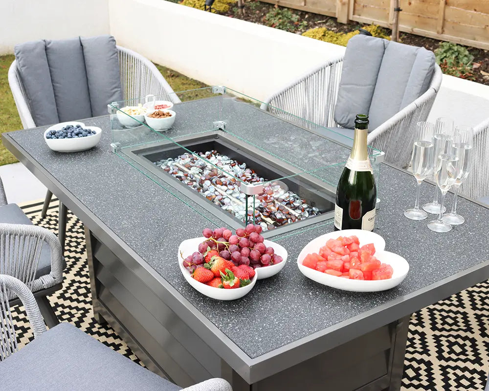Outdoor fire pit dining table with grey chairs and drinks setup