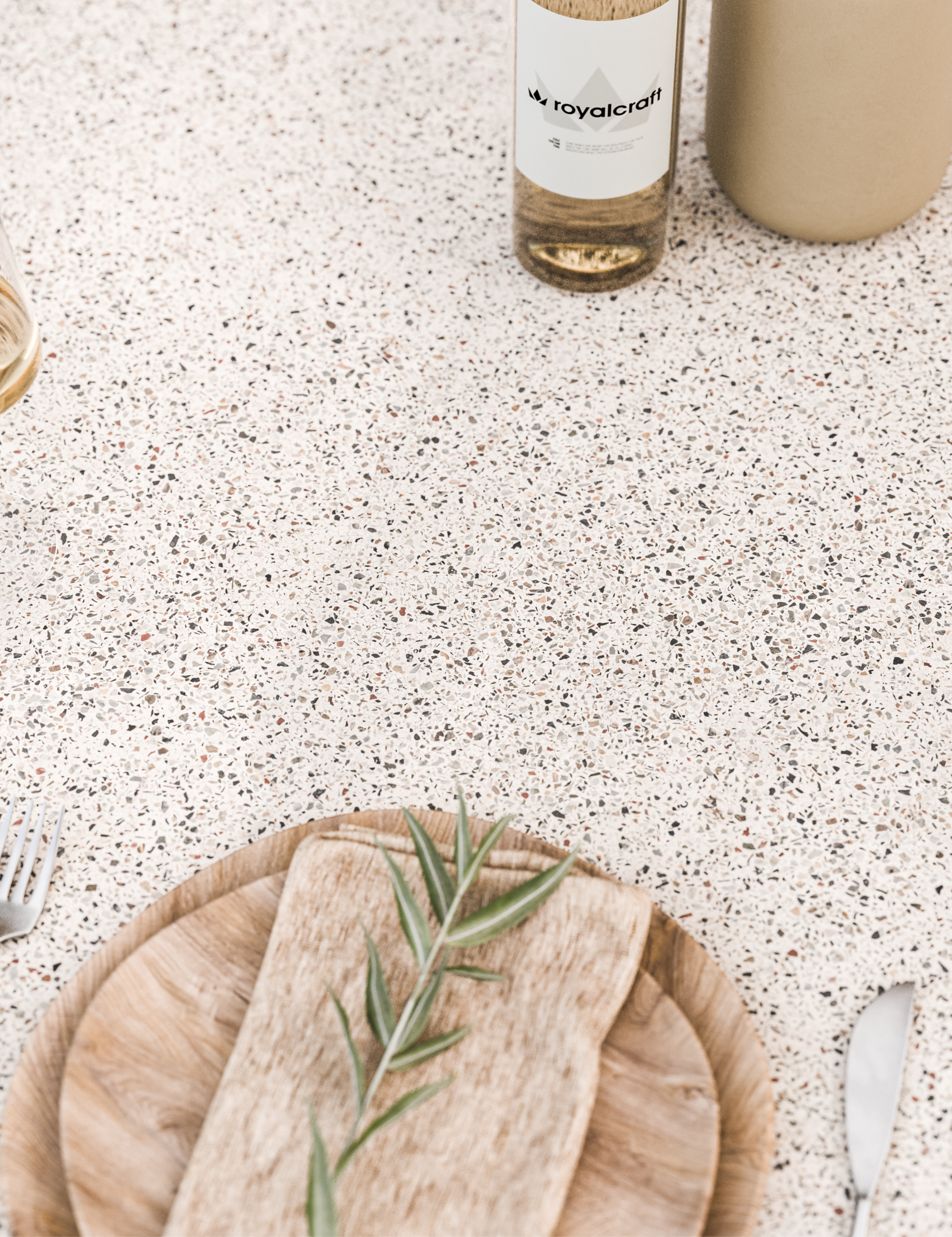 Light terrazzo table surface styled with natural wood plate and neutral décor items