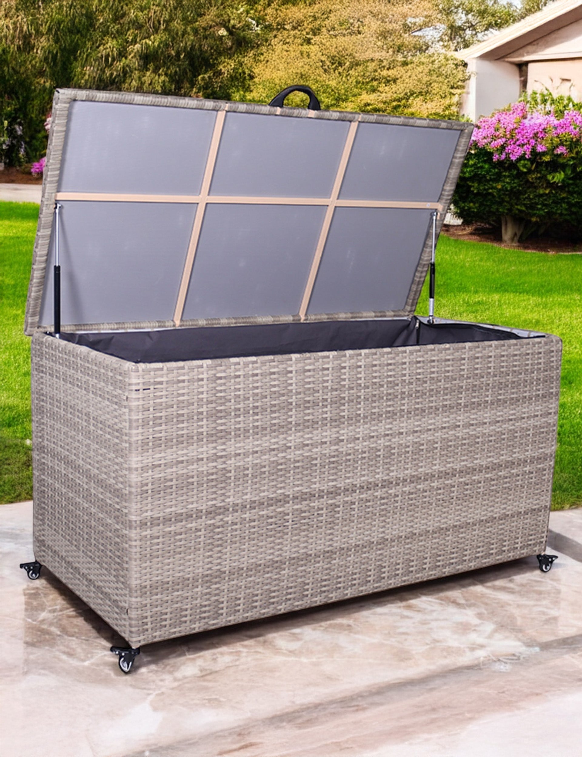 Light grey rattan outdoor storage box with open lid on patio