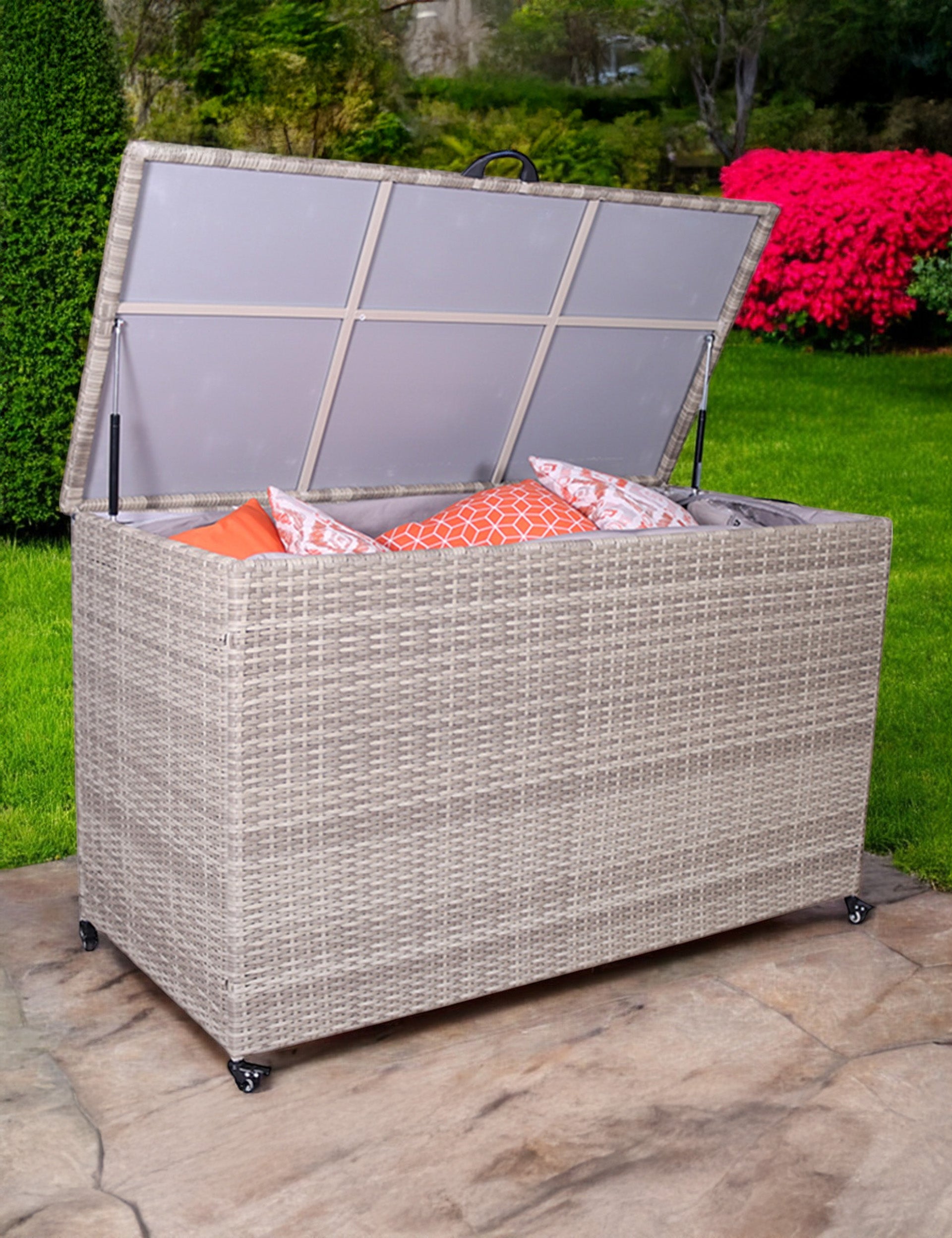 Light grey rattan outdoor storage box with open lid showing cushions inside