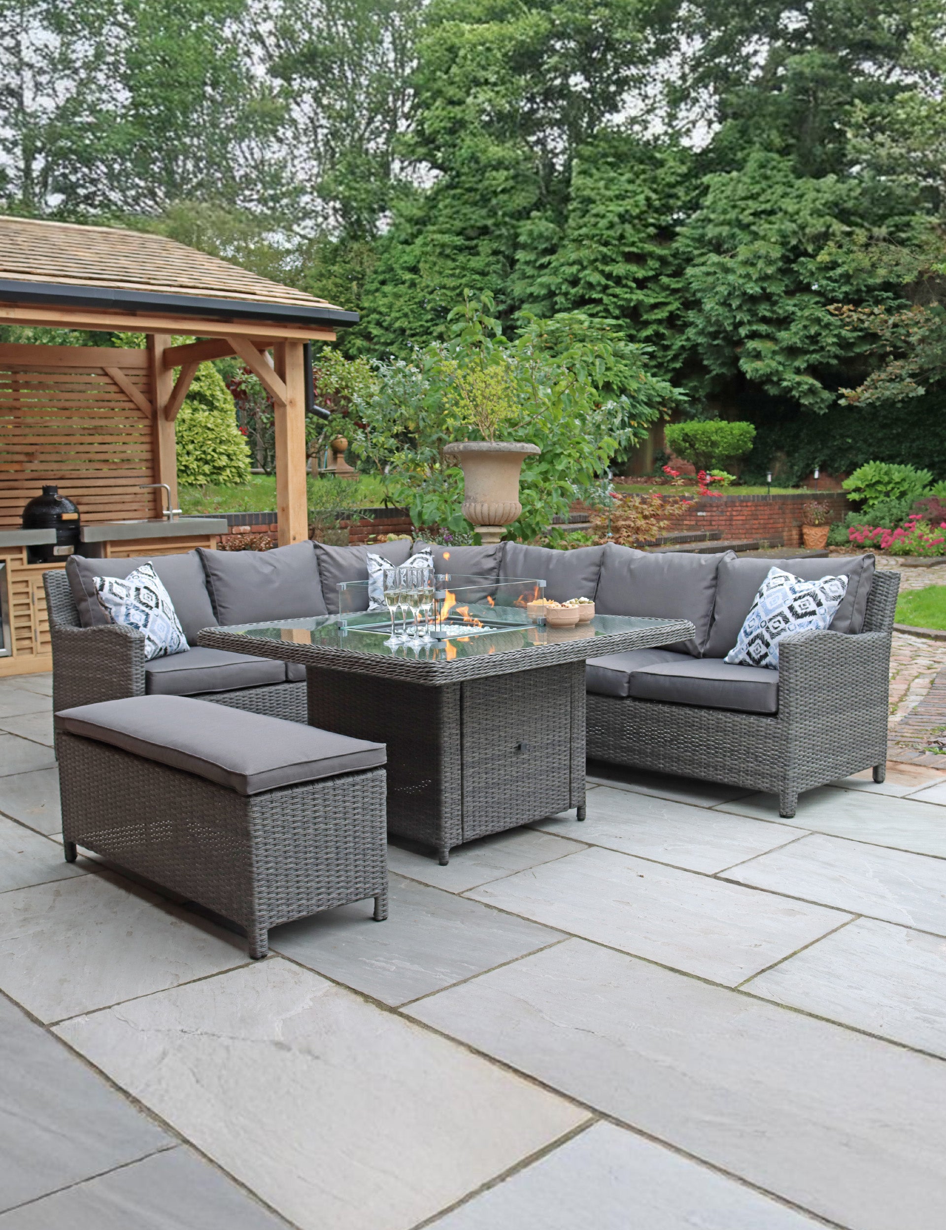 Grey rattan corner sofa set with bench and table on patio