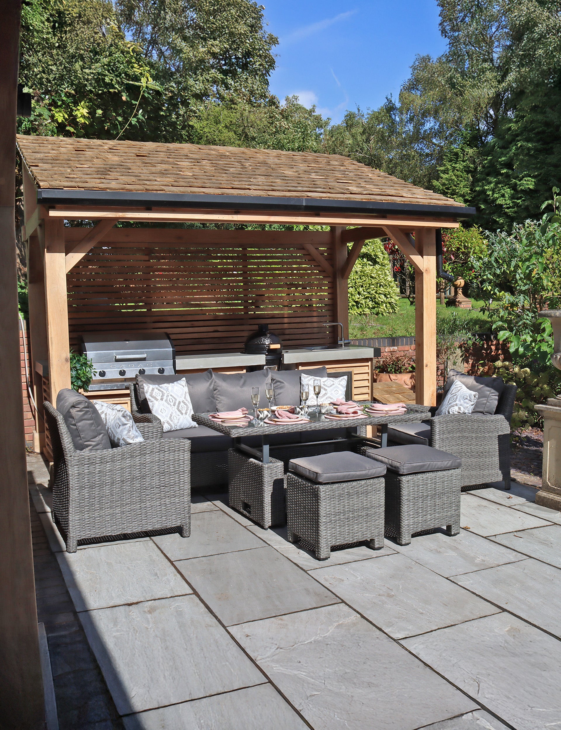 Grey rattan outdoor dining set with sofa, chairs, stools, and table