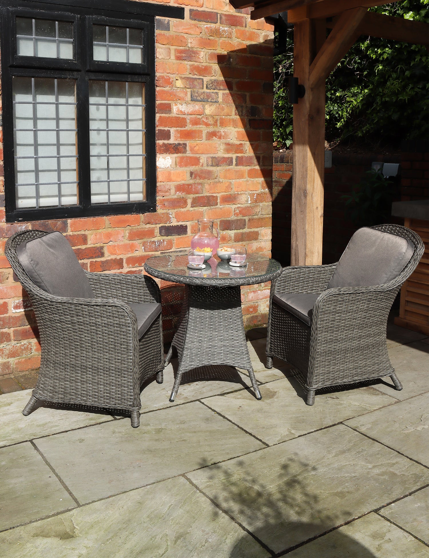 Grey rattan bistro set with round table and two cushioned chairs