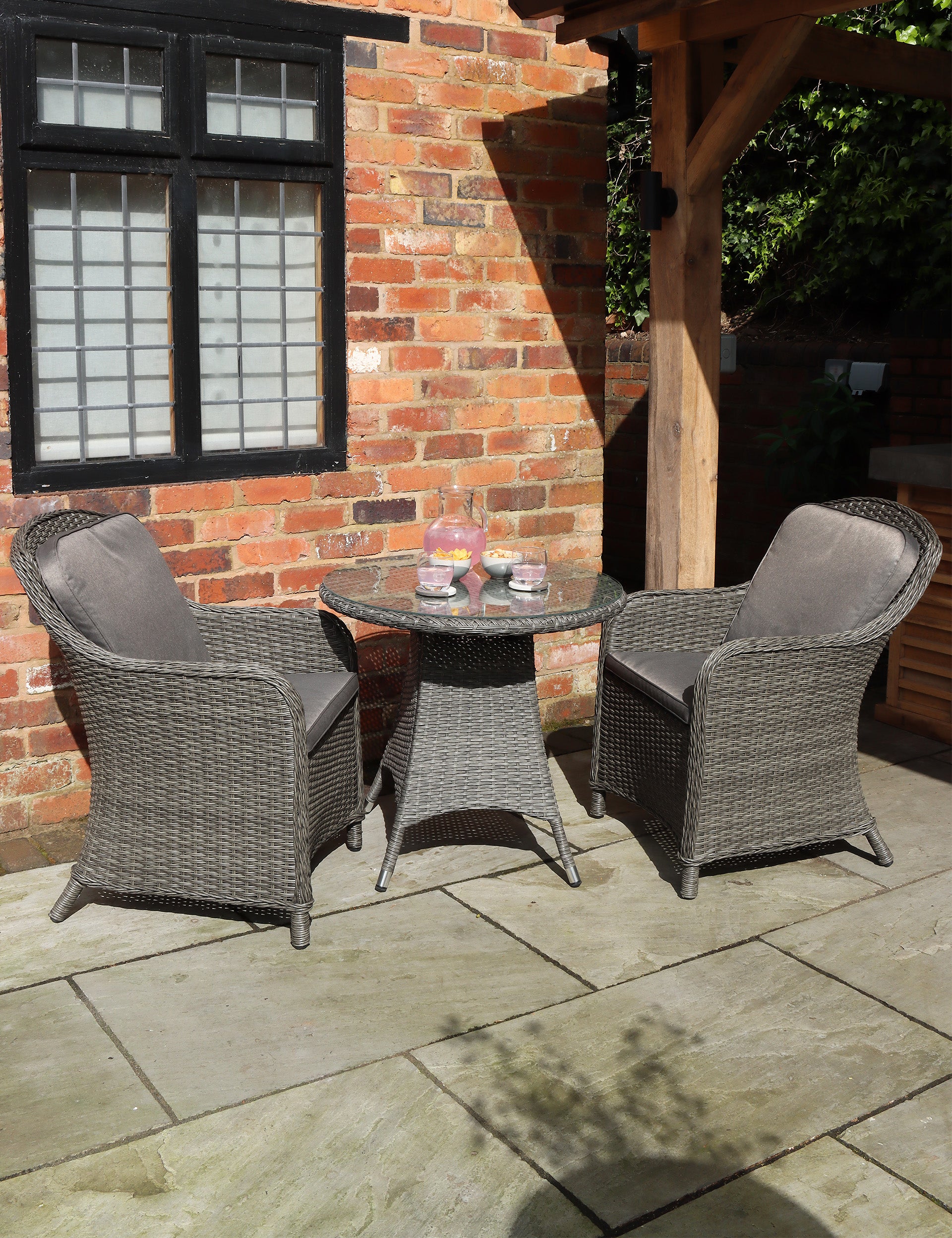 Grey rattan bistro set with round table and two cushioned chairs