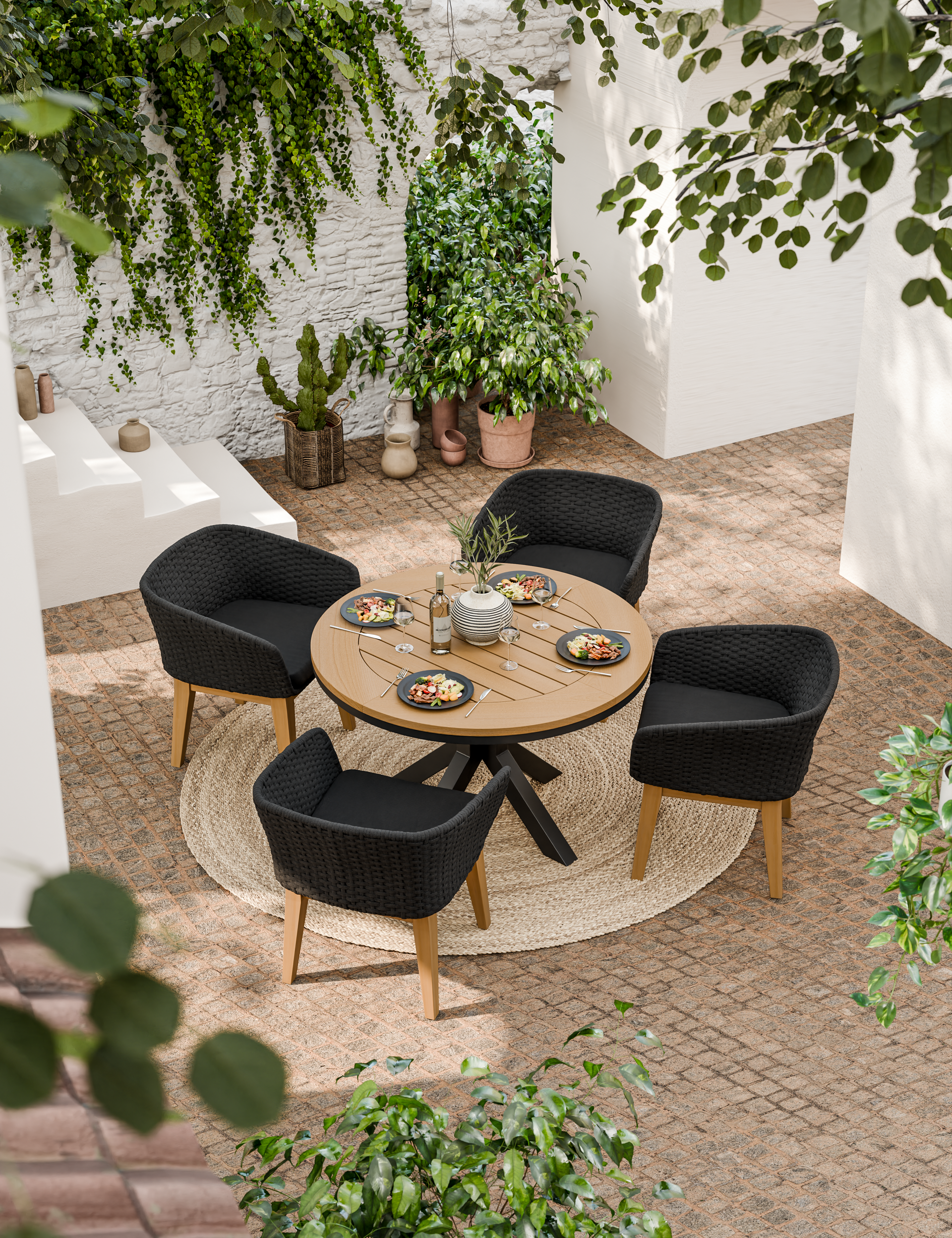 Round wooden dining table with four black cushioned chairs outdoors