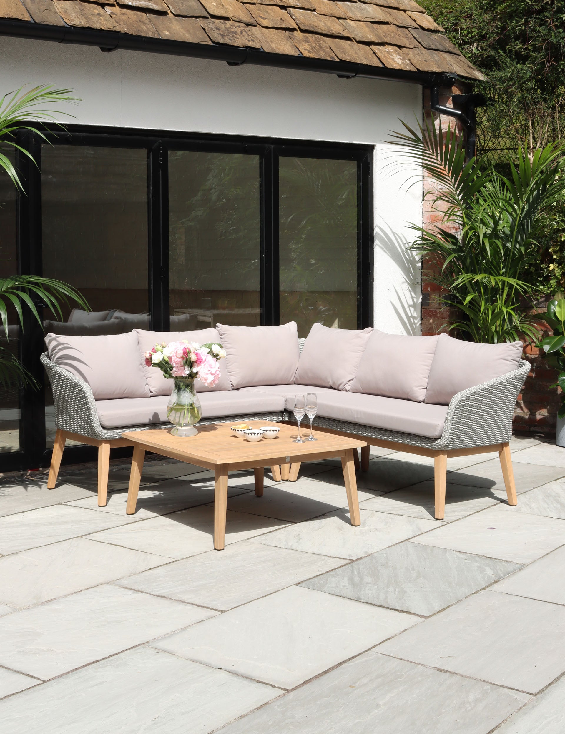 Light grey corner outdoor sofa with cushions and wooden coffee table