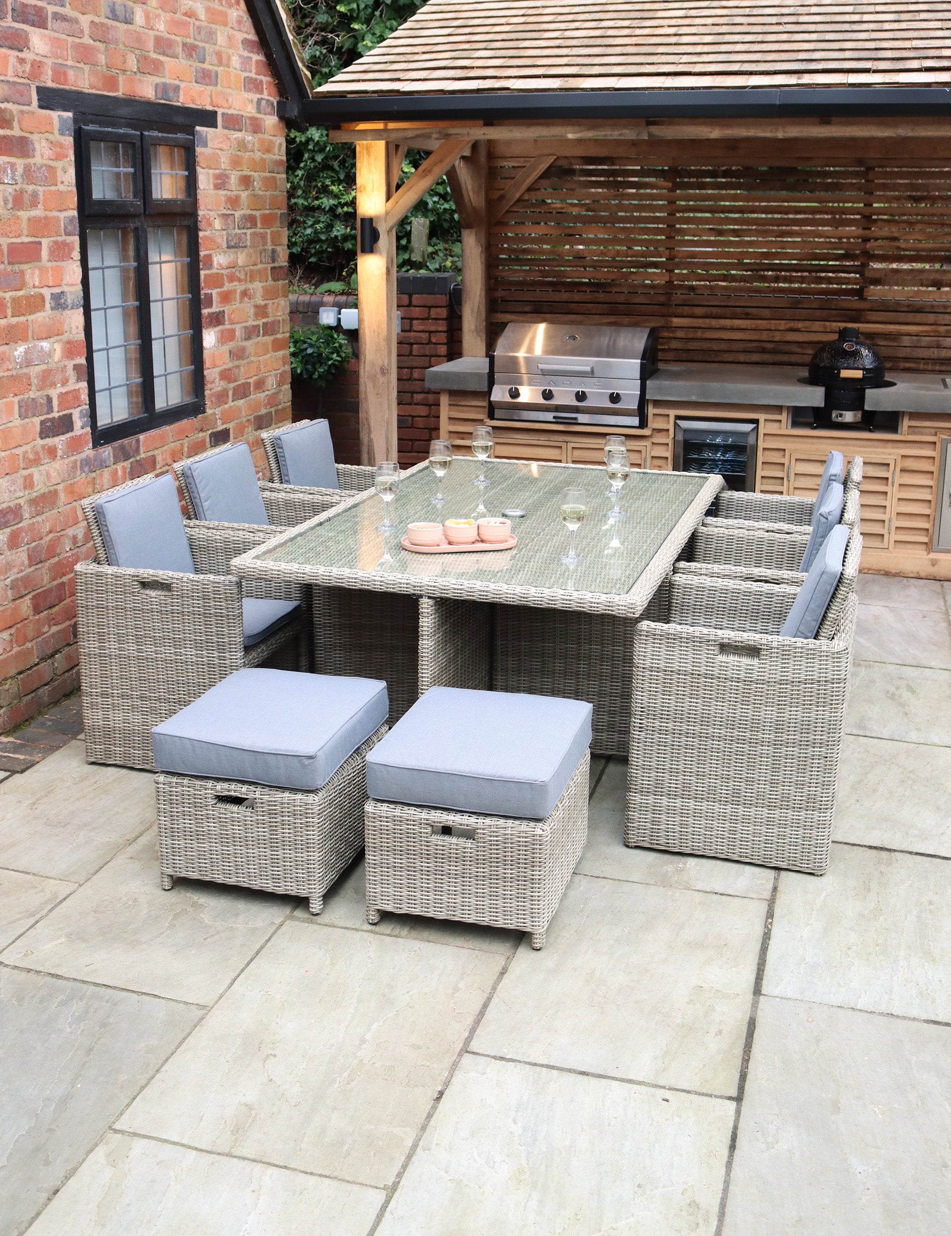 Rattan dining set with eight grey cushioned chairs and glass-top table