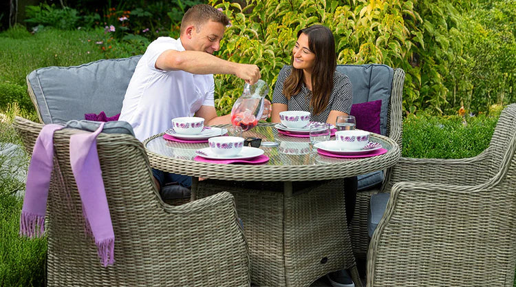 Two people sitting at a round outdoor dining table with chairs and a scarf.