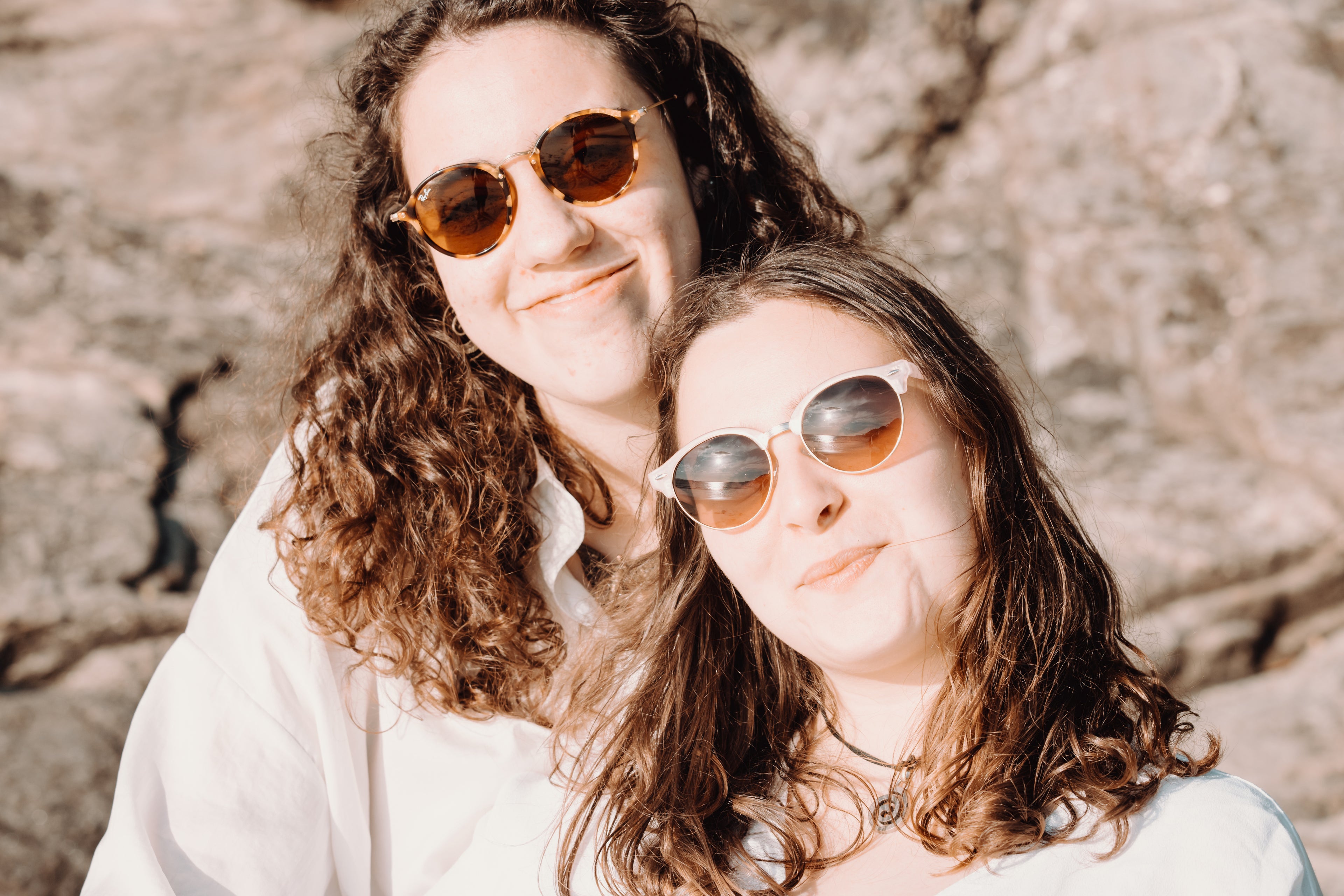 Two women wearing sunglasses smiling for the camera