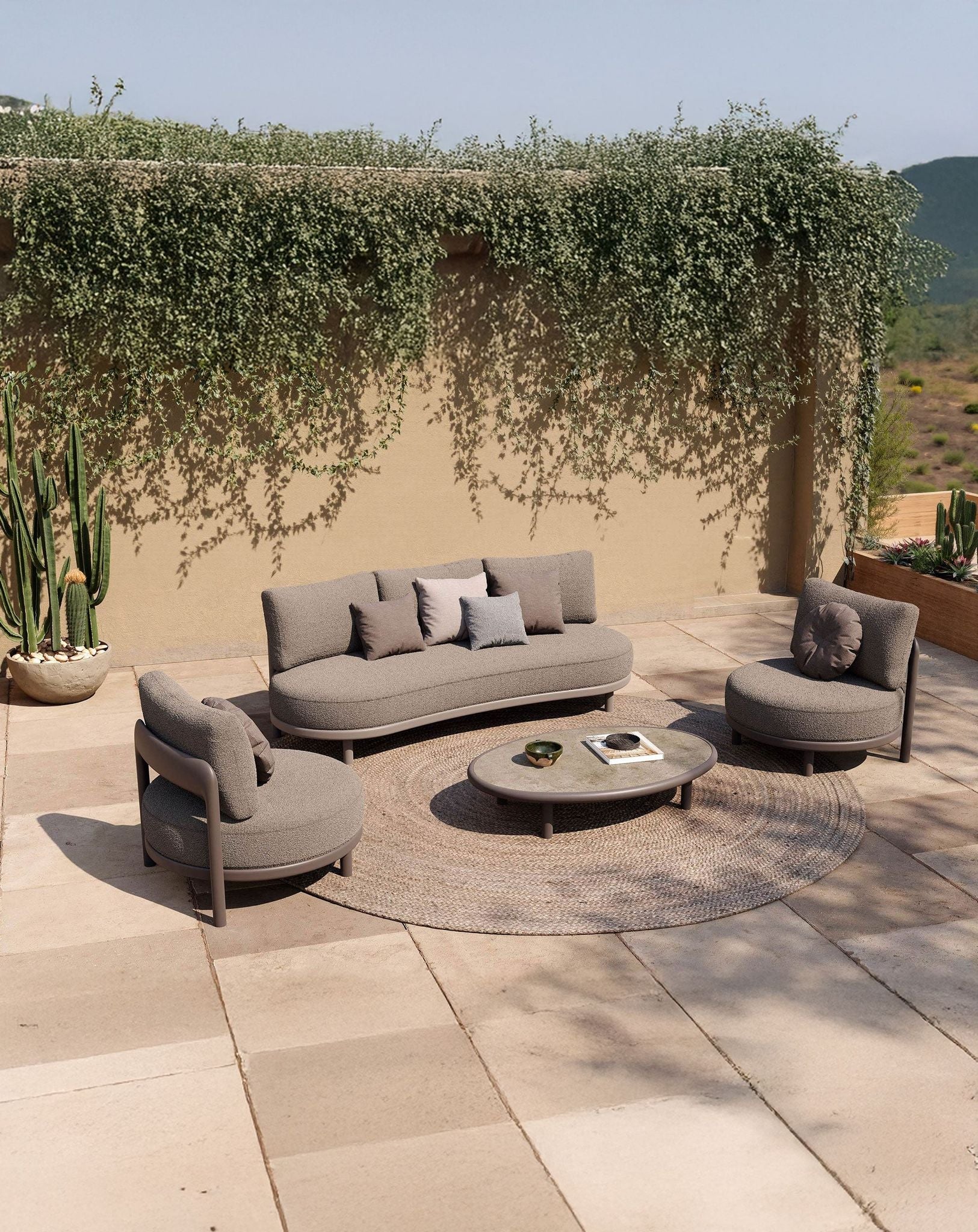 Image of Outdoor patio with gray sofa set and round coffee table under a canopy of greenery.