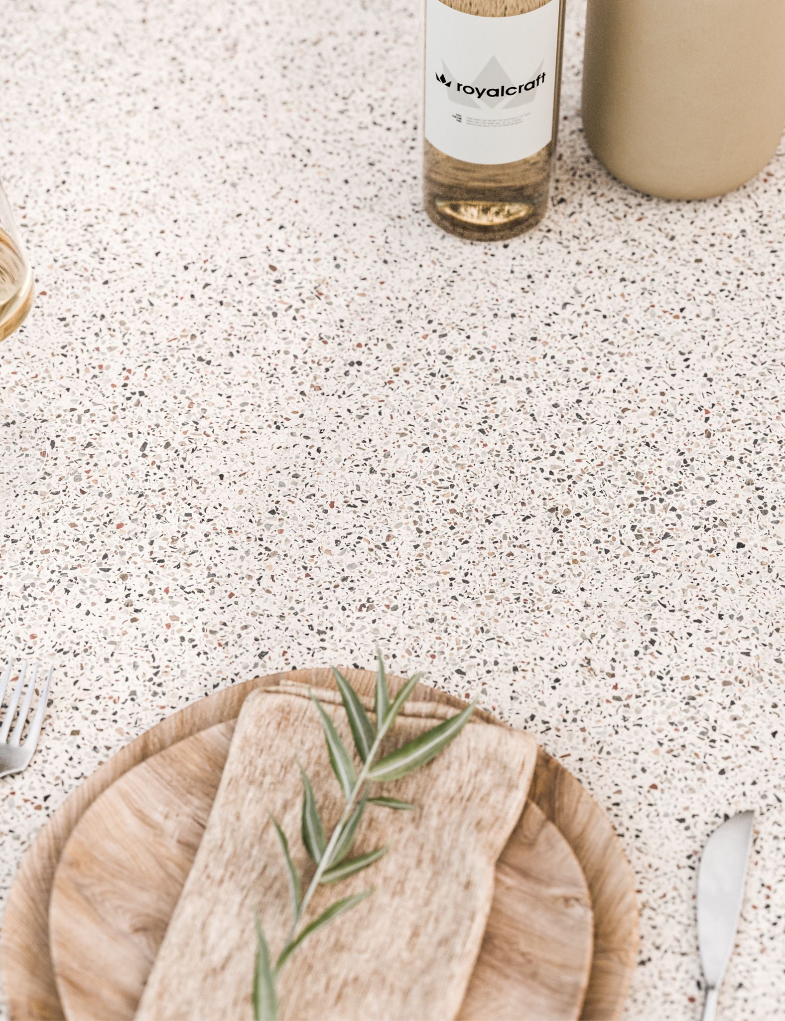 Light terrazzo table surface styled with natural wood plate and neutral d√©cor items