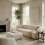 Modern living room with beige sofa, ottoman, and decor elements.