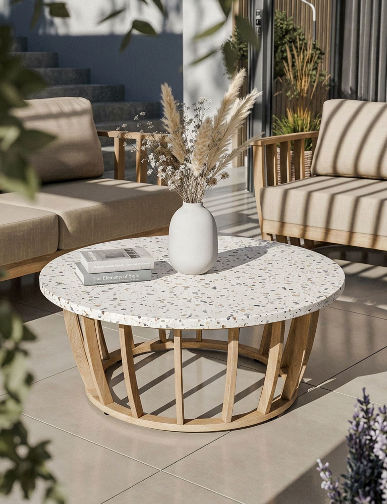 Image of Round outdoor coffee table with a white speckled stone top and a light natural wood frame, styled in a patio setting with a white vase and books on top.