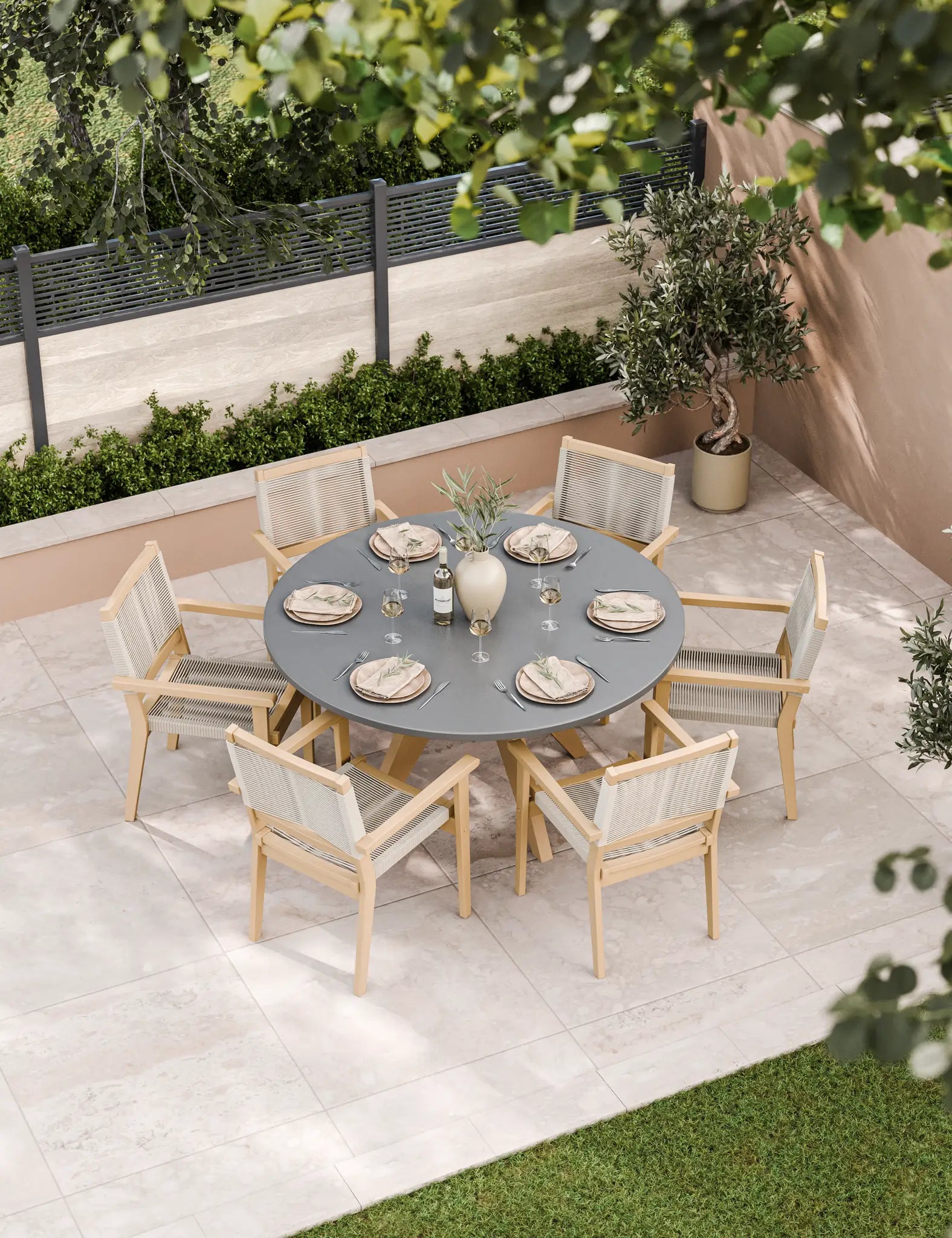 Round grey outdoor dining table with six wooden chairs with cushions