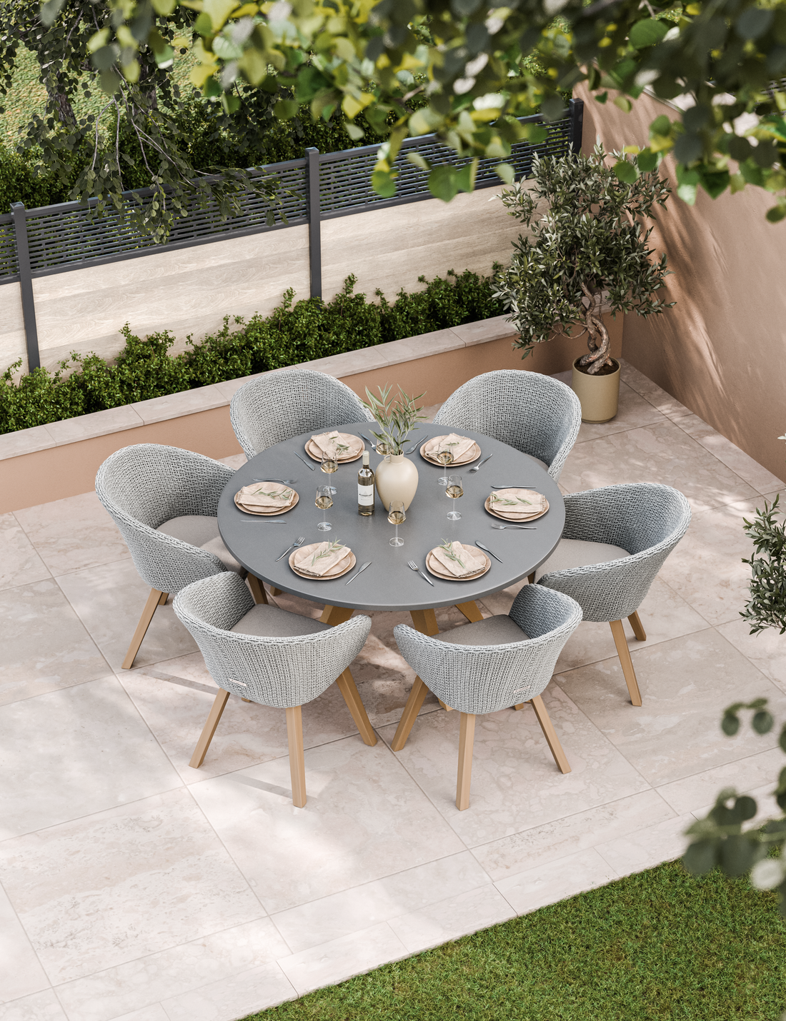 Round grey outdoor dining table with six cushioned chairs on patio