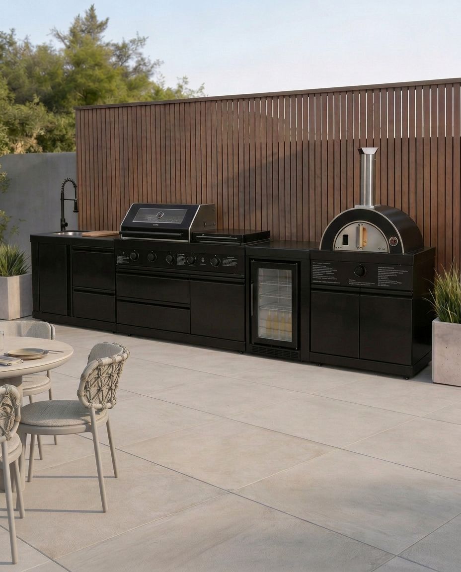 Image of Outdoor kitchen setup with black grill, refrigerator, and pizza oven on a patio.