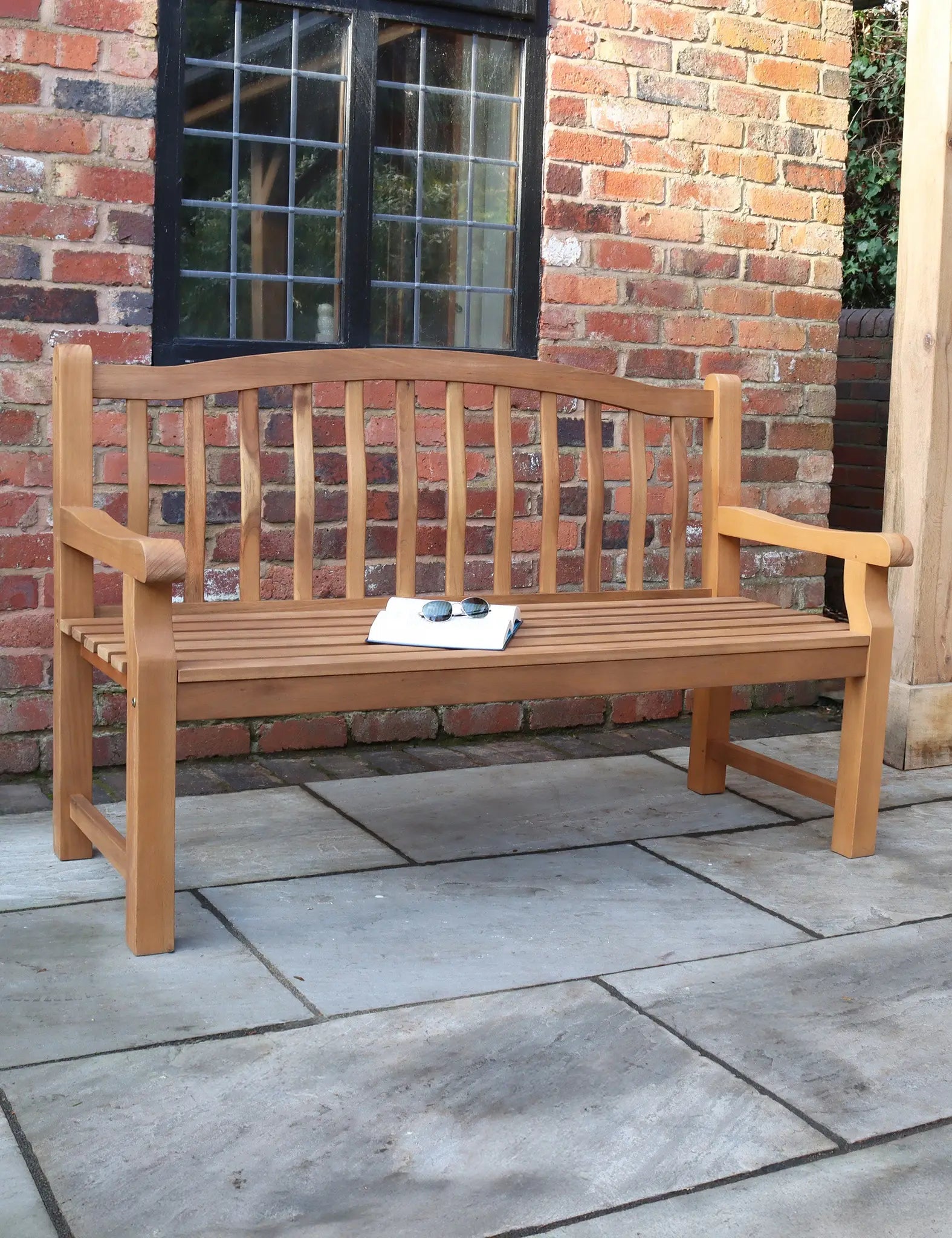 Wooden outdoor garden bench with slatted backrest and armrests on patio