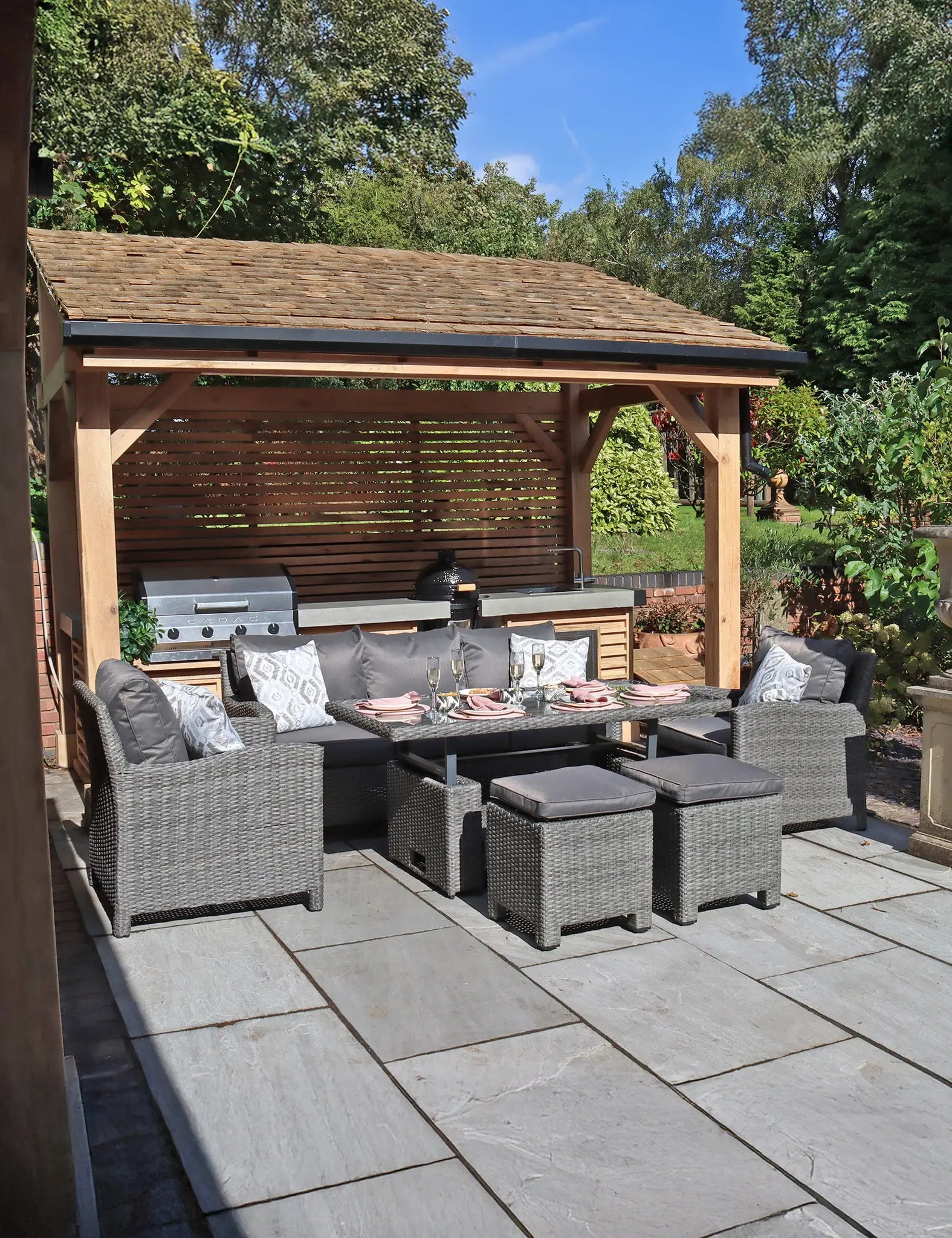 Image of Grey rattan outdoor dining set with sofa, chairs, stools, and table