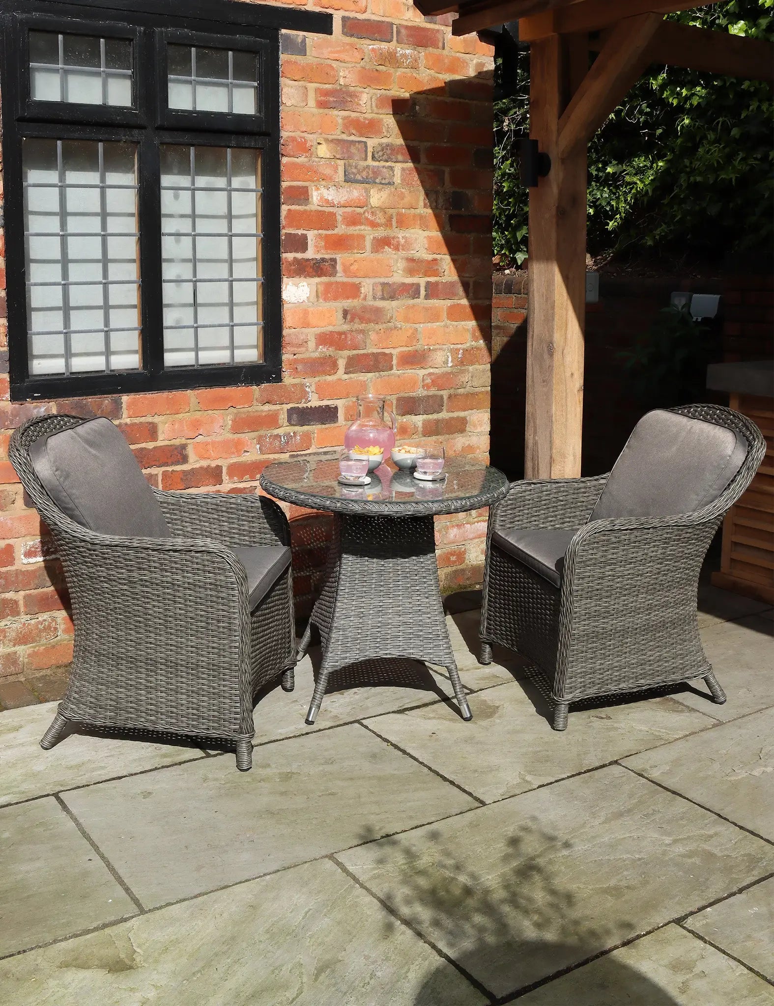 Grey rattan bistro set with round table and two cushioned chairs