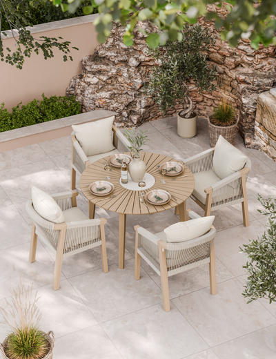 Round wooden outdoor dining table with cushioned chairs on patio