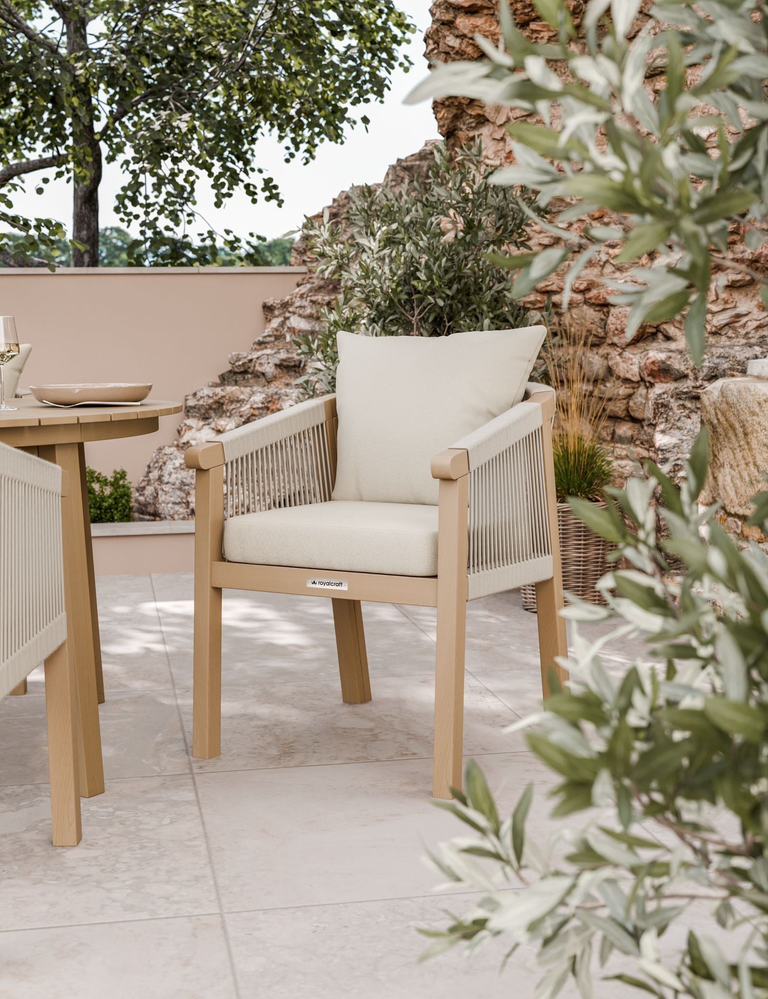 Image of Outdoor furniture set with wooden chairs and table on a patio with plants and stone wall.
