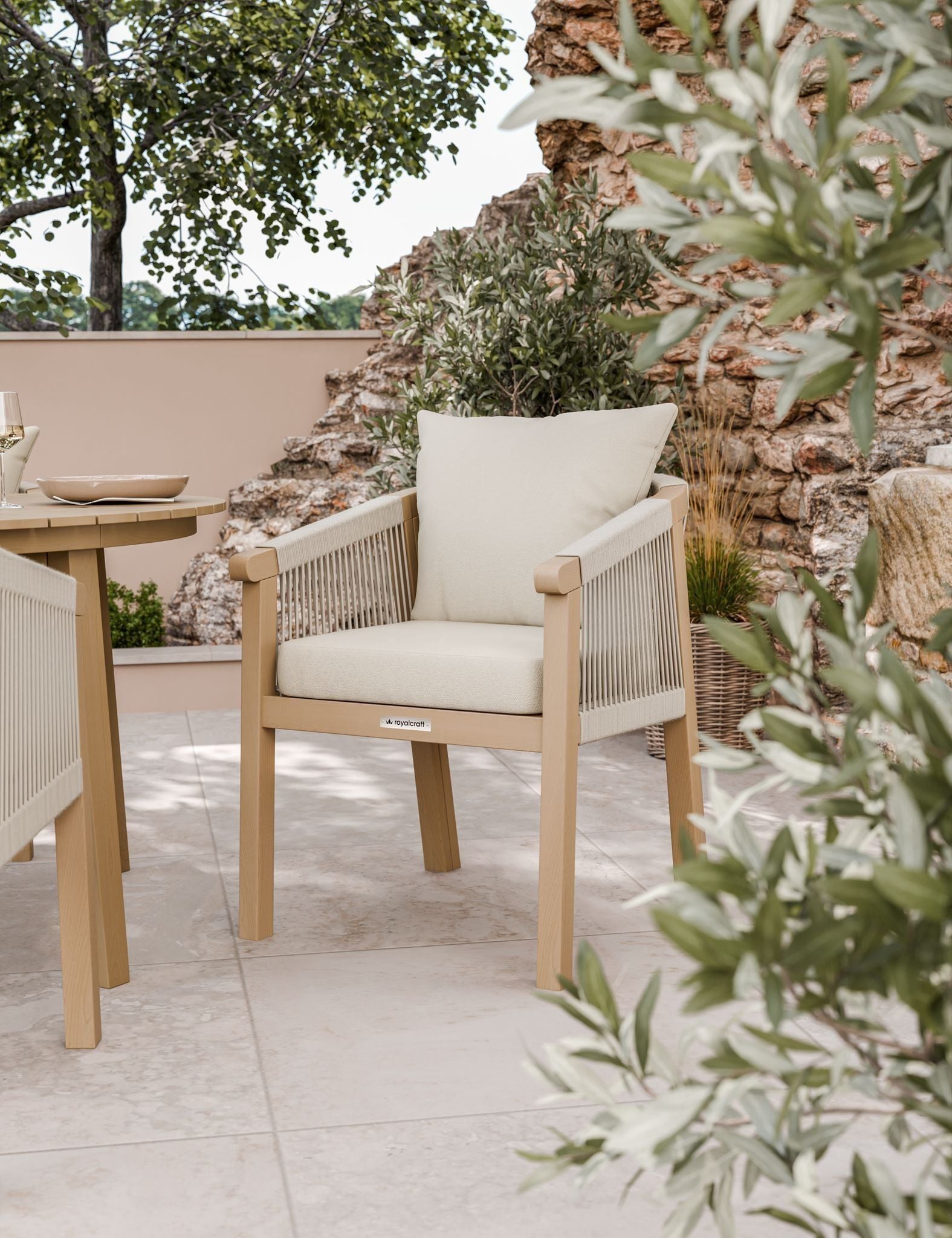 Image of Outdoor furniture set with wooden chairs and table on a patio with plants and stone wall.