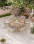 Round outdoor dining table with six cushioned rope chairs