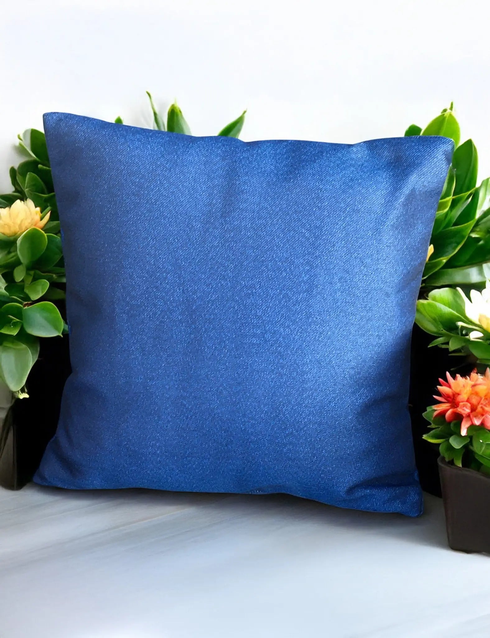 Image of Blue outdoor cushion with plain design surrounded by flowers