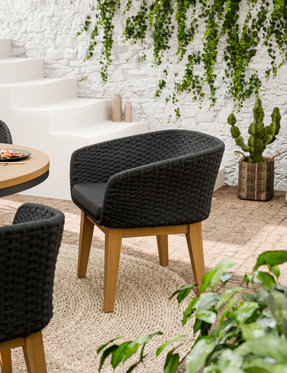 Black cushioned outdoor dining chair with wooden legs on patio