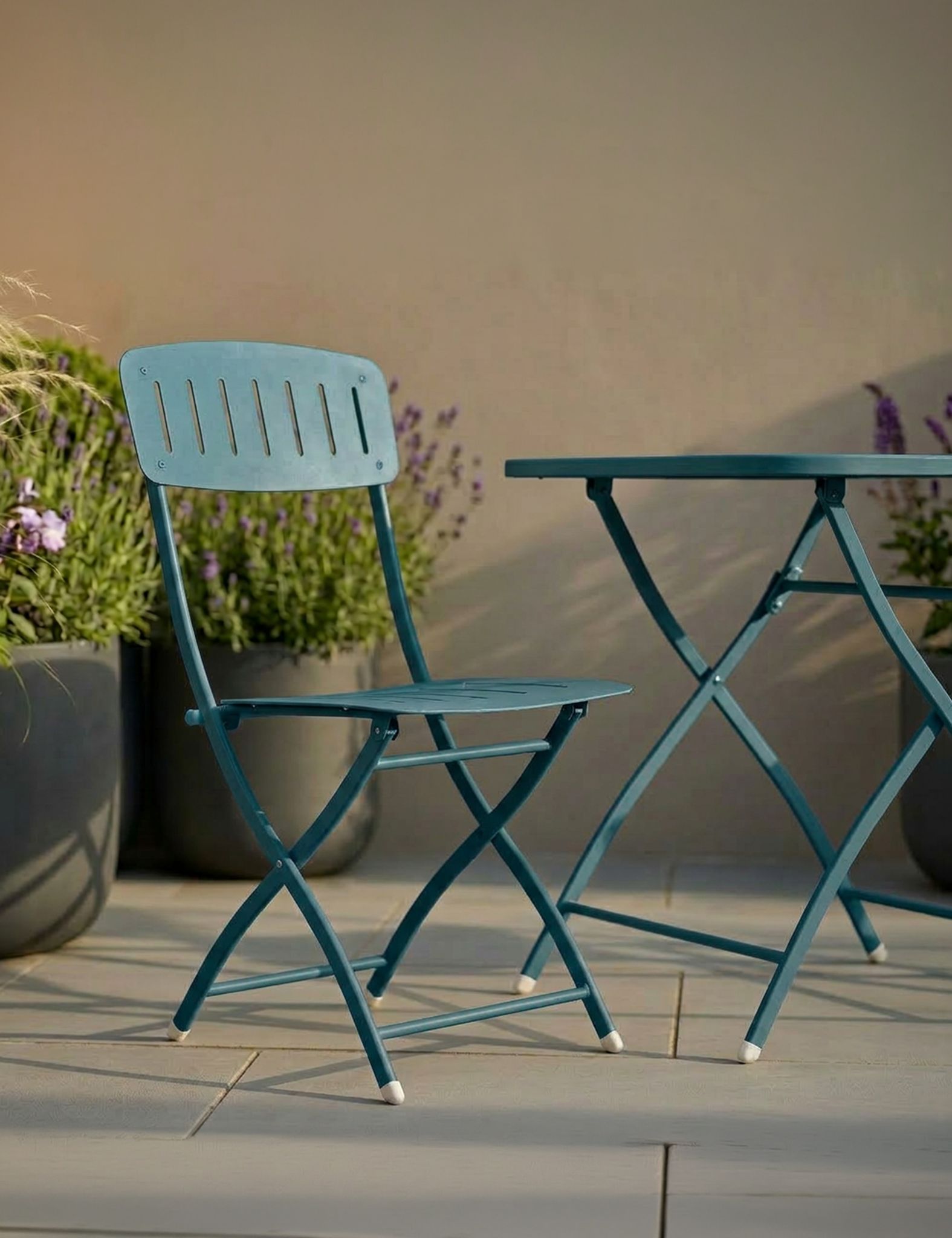 Image of outdoor folding table and chair set on a patio with plants in the background