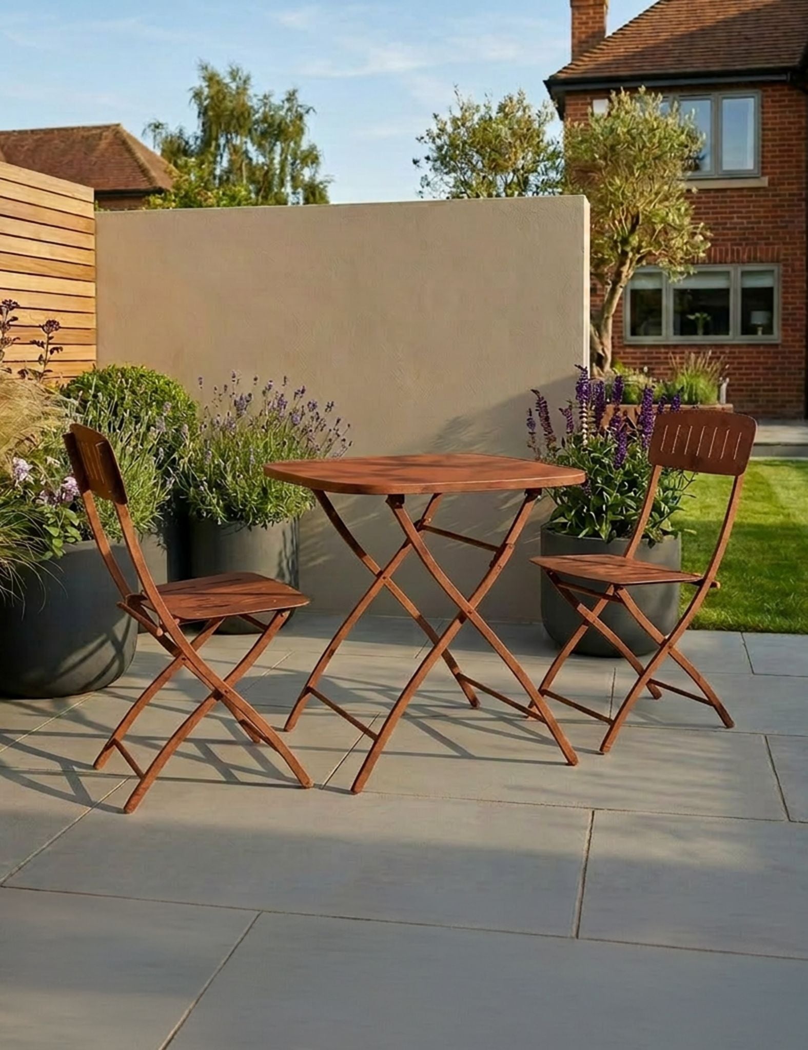 Image of Wooden outdoor table and chairs on a patio with garden and house in the background