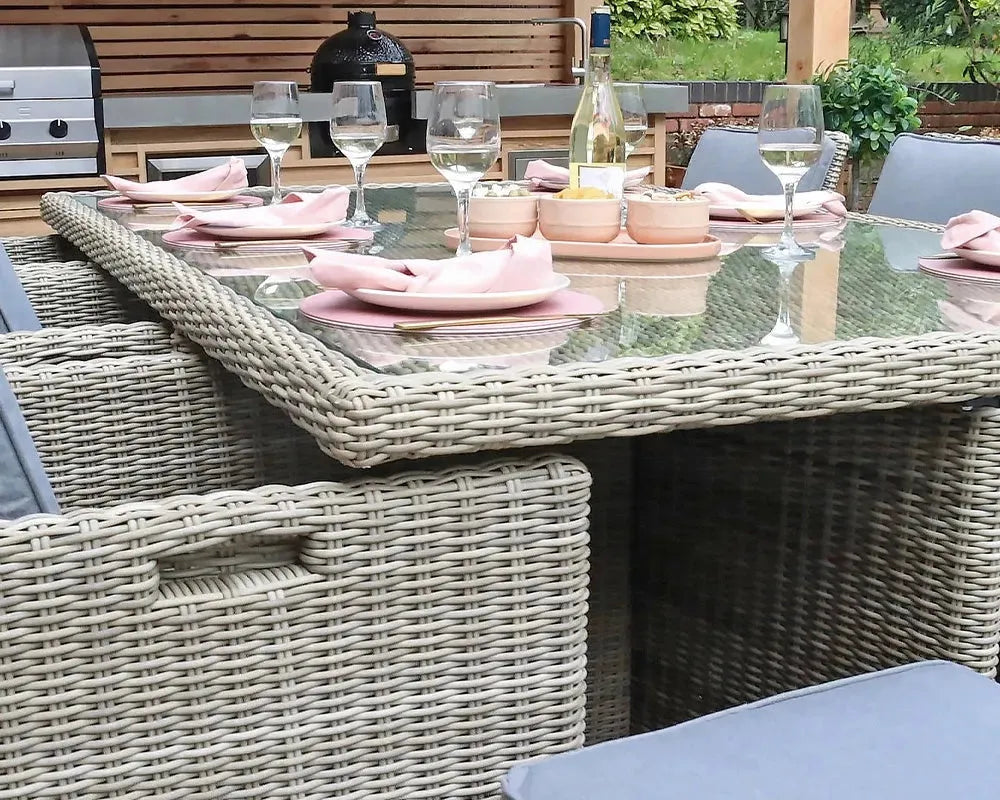 Image of Outdoor dining setup with Rattan table and chairs, glasses, and bottles.