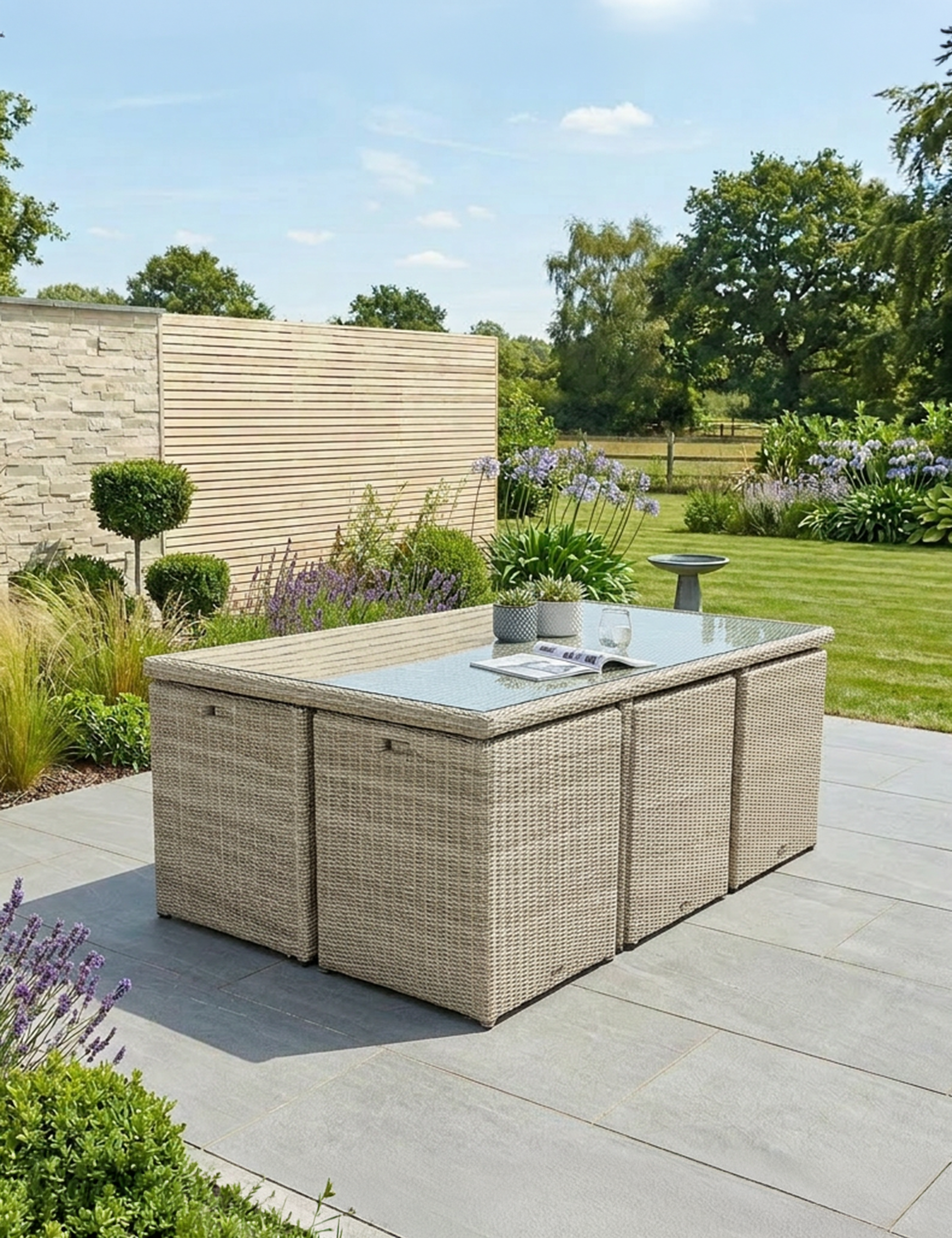 Image of Outdoor patio set with glass top table and storage boxes on a patio area with garden background.