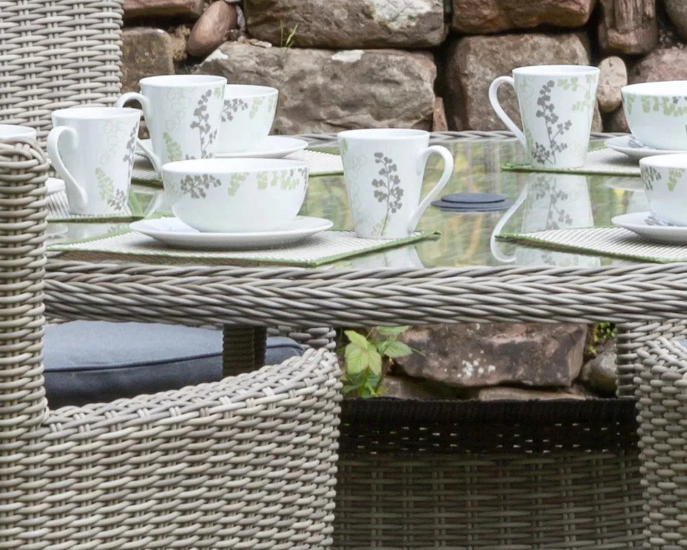 Image of Ceramic cups and saucers on a wicker table outdoors with stone wall background