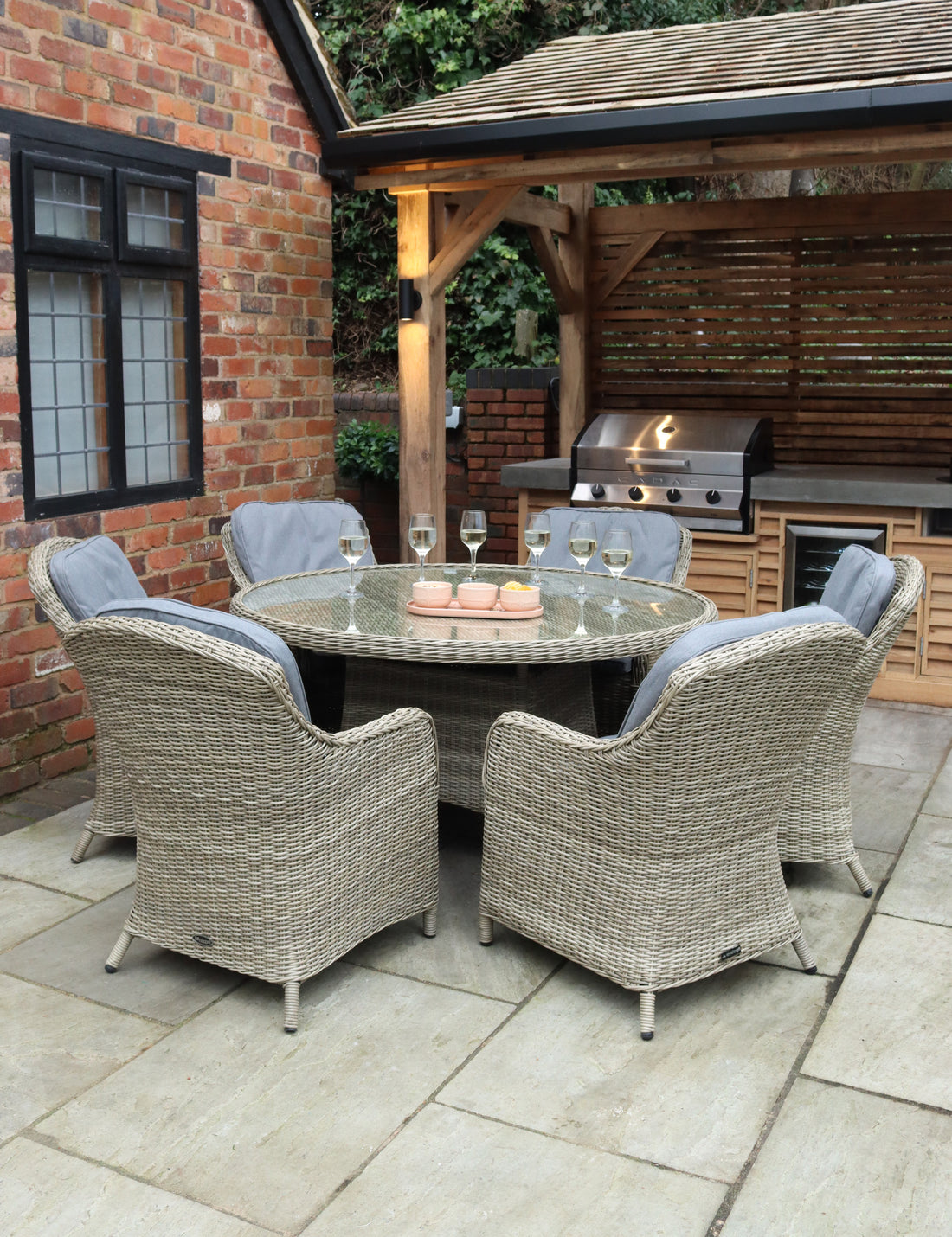 Rattan patio dining set with glass-top table and six cushioned chairs