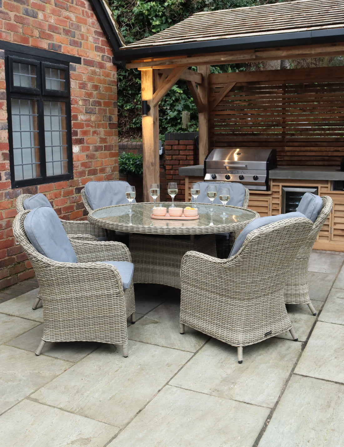 Rattan dining set with round glass-top table and six grey chairs