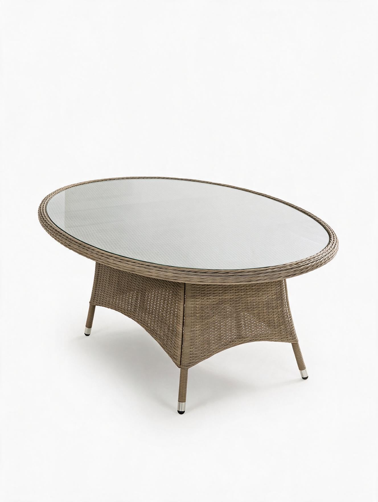 Image of An oval outdoor coffee table made of woven wicker with a clear glass top and four tapered metal legs, shown on a white background.