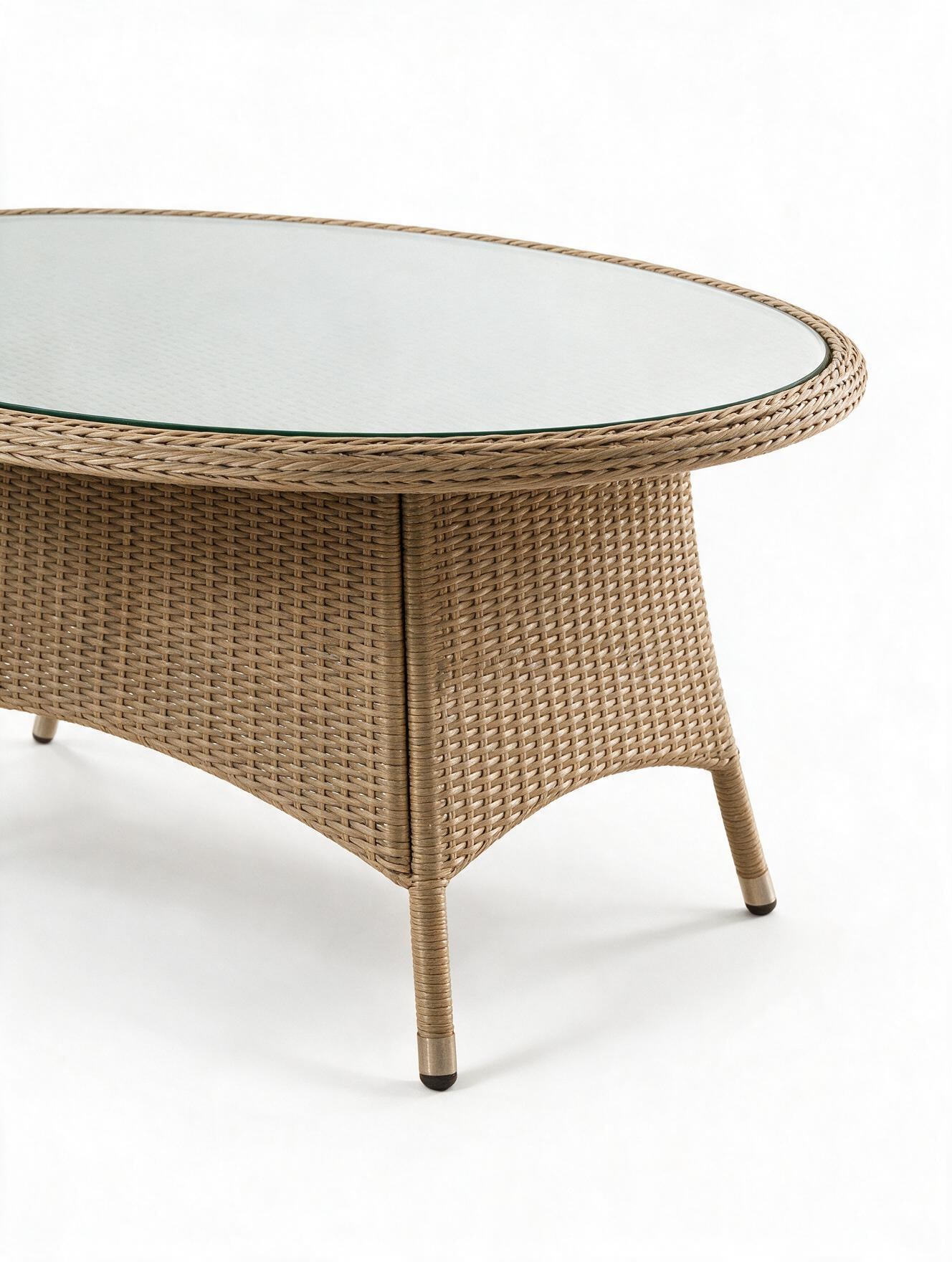 Image of An oval outdoor coffee table with a woven wicker base in a natural tan color and a clear glass top, shown on a white background.