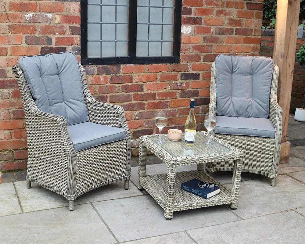 Image of Outdoor patio set with two chairs and a table against a brick wall.