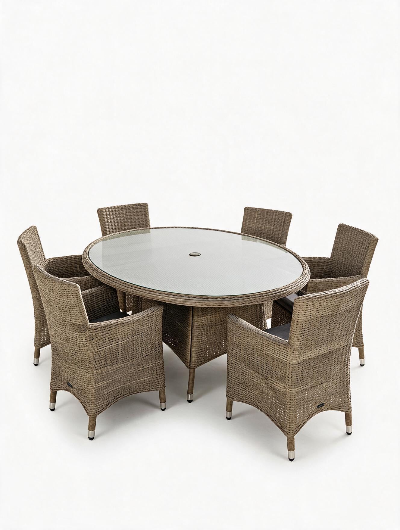Image of A 7-piece outdoor dining set featuring a round glass-top table and six woven wicker armchairs in a taupe-brown color, shown on a plain white studio background.