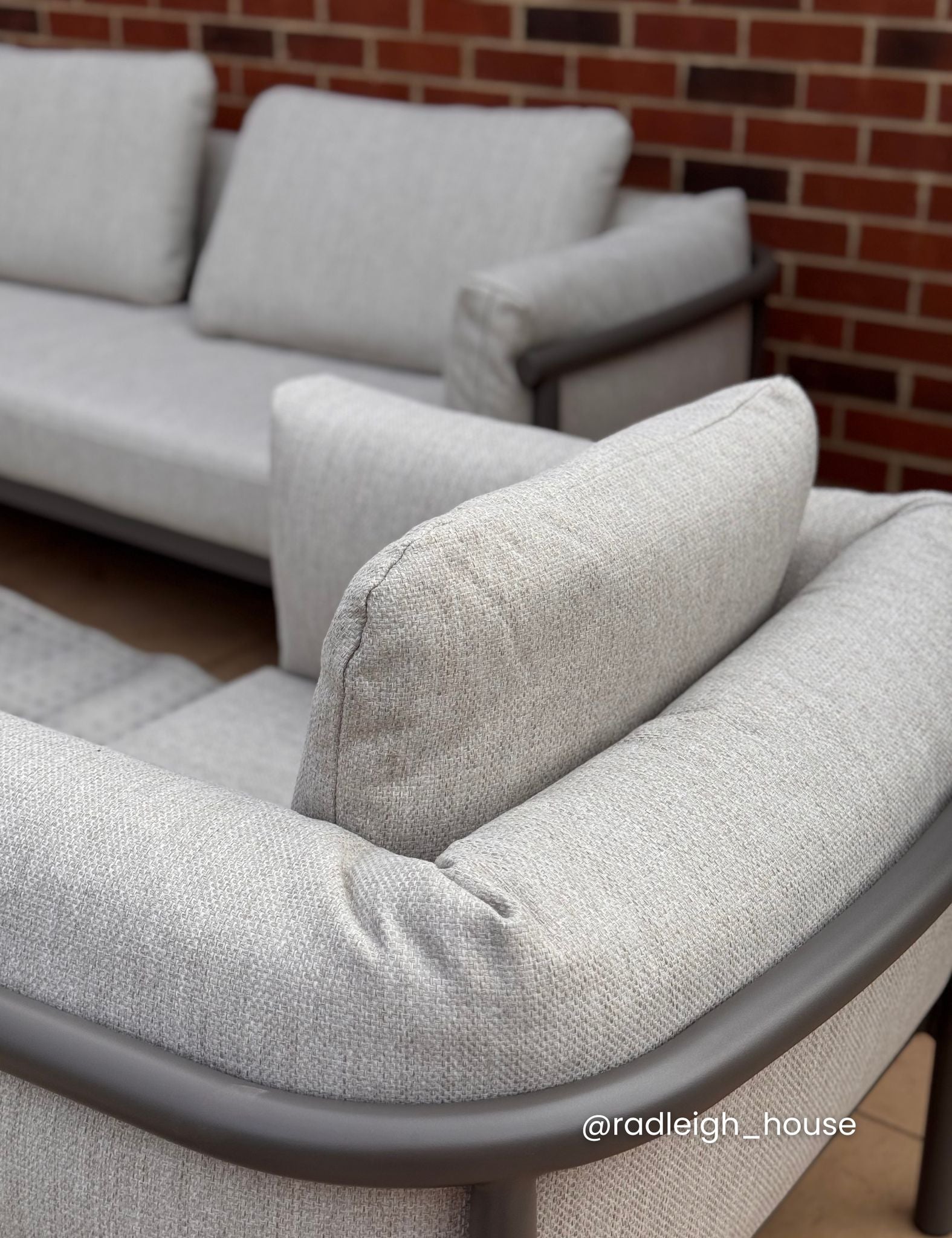 Image of Gray fabric sofa with cushions against a brick wall